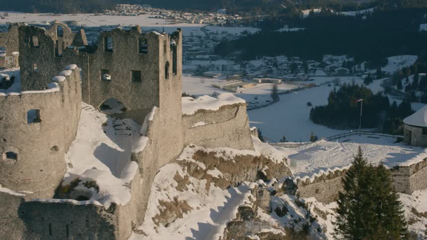 The castle has broken walls and is filled with snow on the mountain