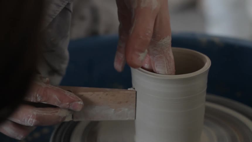 A person works with clay on a ceramics wheel