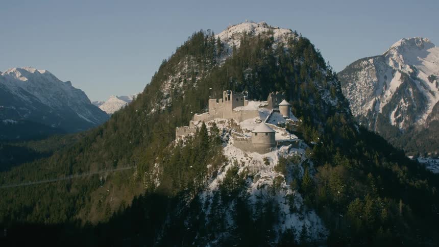 An old abandoned castle sits atop a snow covered mountain