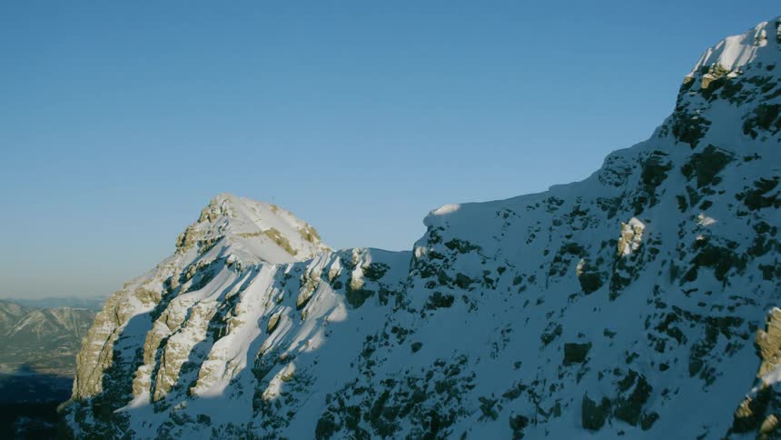 A plane is flying up towards the top of a mountain