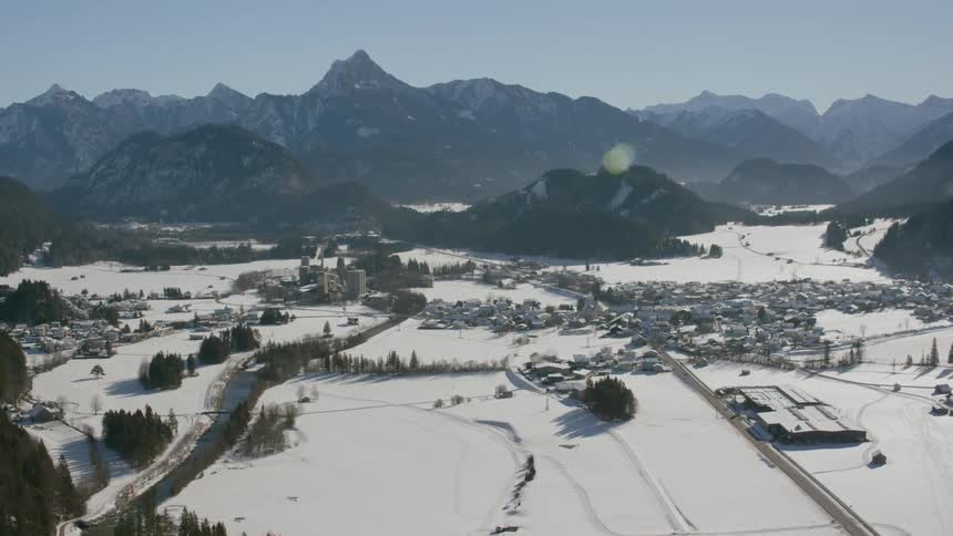 A river runs through a village in a snow covered valley on a sunny day