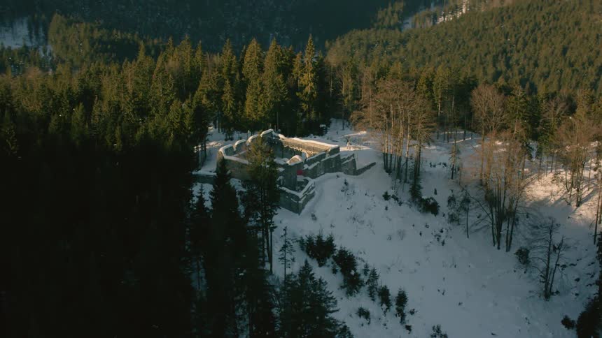 A ruined building on a mountainside sits covered in snow