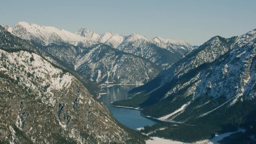 A mountain lake is reflecting the landscape around it on a sunny day