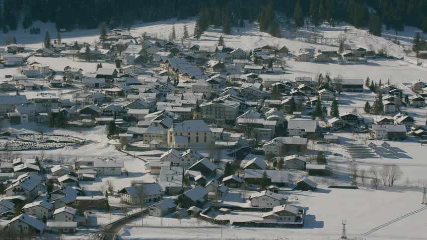 The town below has many houses and is lined with a mountain