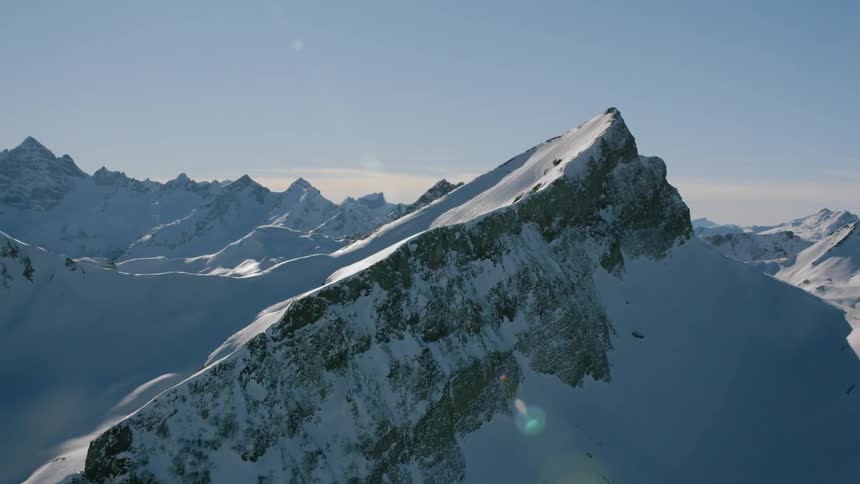 The sun is shining on jagged mountain peaks covered with snow