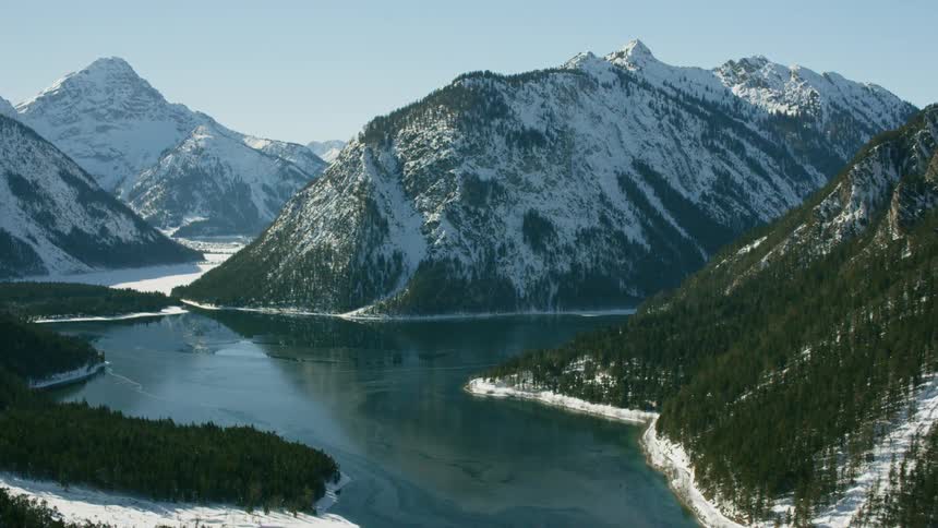 River runs through snowy mountains and tree lined banks