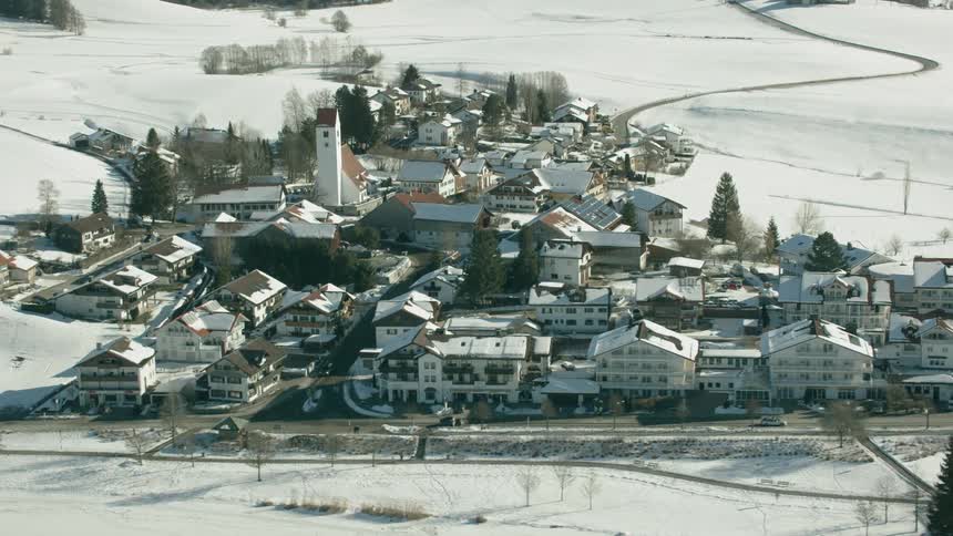 Cars drive by buildings in a small town