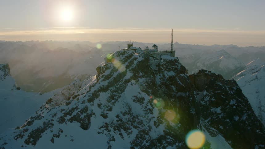 Building sits atop snowy mountain at sunset