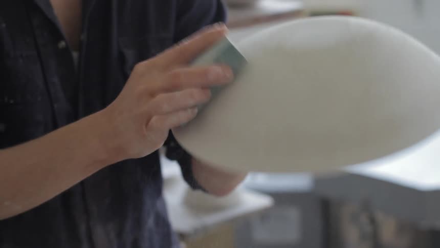 A bowl is sanded in a pottery studio