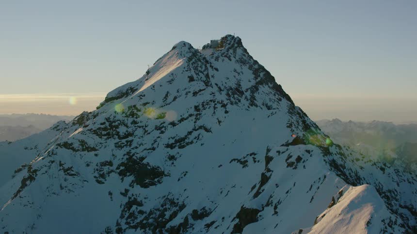 The sun sets over snowy mountains