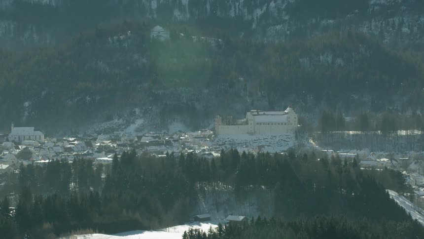 An old castle towers above village buildings in a mountain landscape