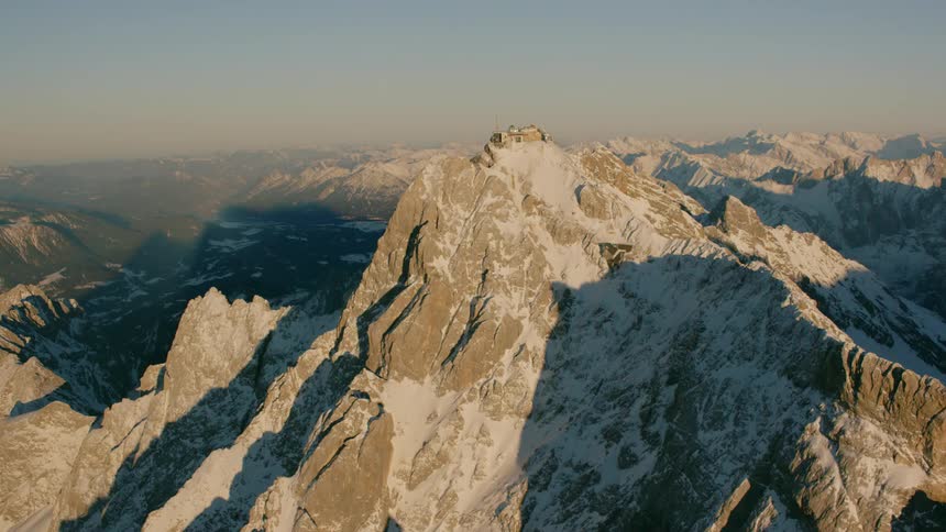 Shadows grow on snow-covered mountains during the day