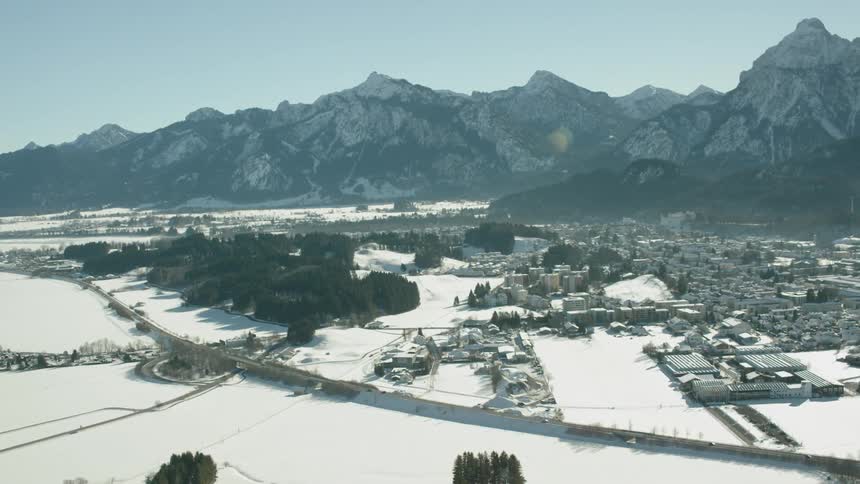 A river is flowing past a village in a mountain valley covered in snow