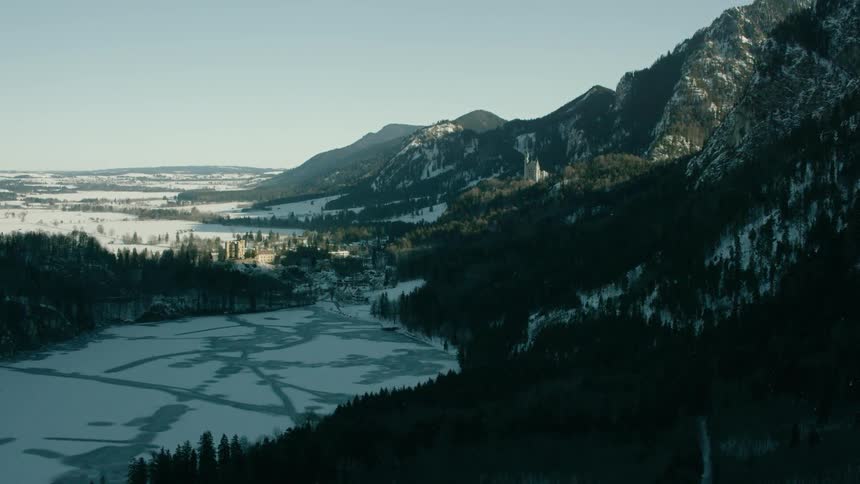 A snow covered lake is at the foot of a mountain