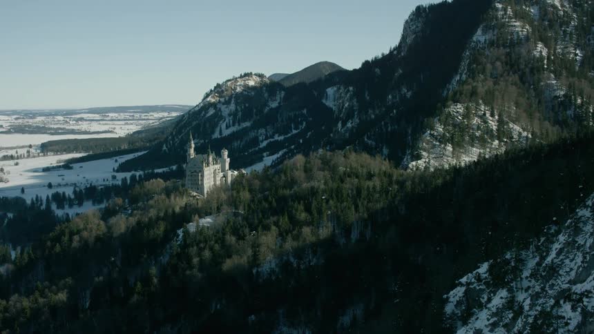 A castle sits perched in snowy mountains