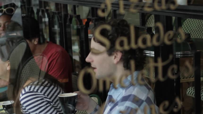 A woman laughs as others sit around talking in a coffee shop