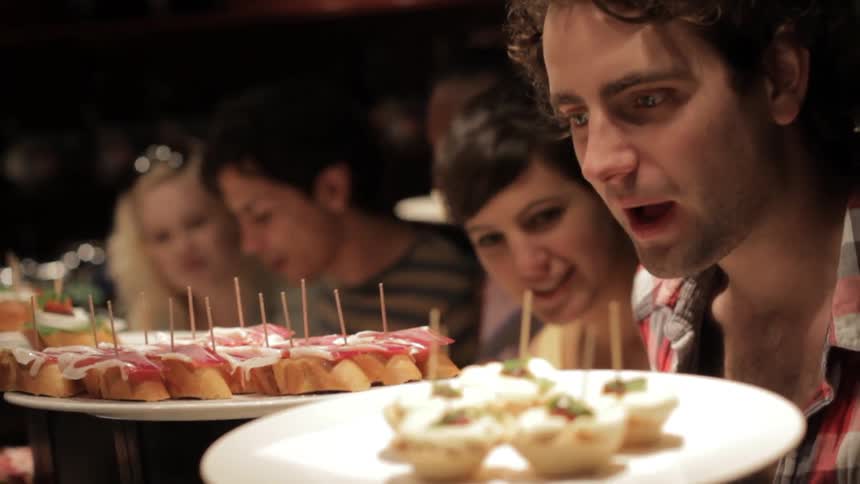 A group of people sit at a table with food on platters