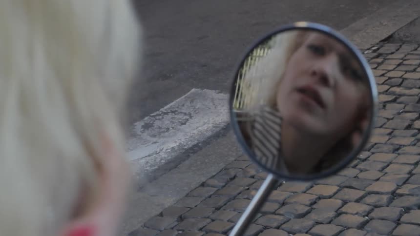 A woman primps in a small mirror