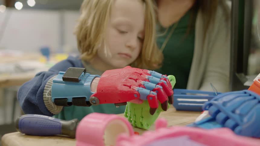 A child uses an autonomous hand sleeve to pick up objects
