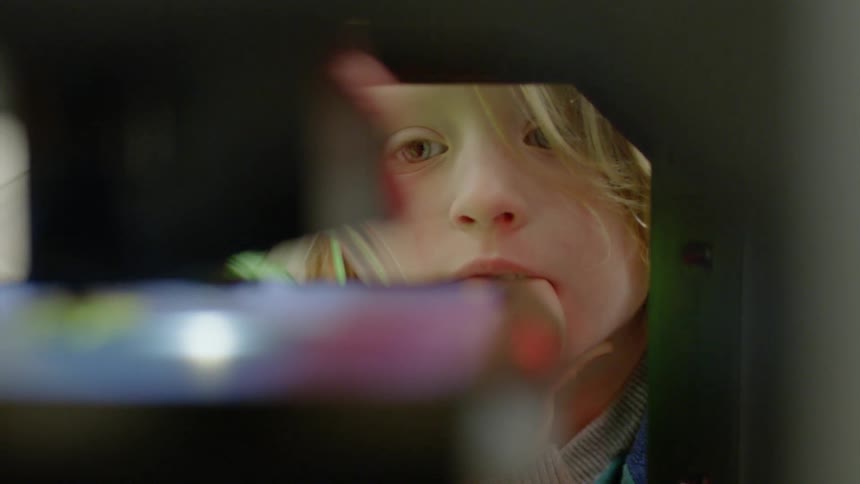 Young boy watches while a 3d printer works and moves