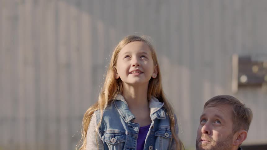 A dad helps his daughter fly and control a drone