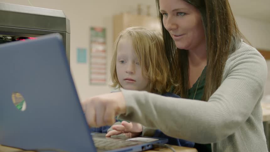 A woman and a kid are using the laptop