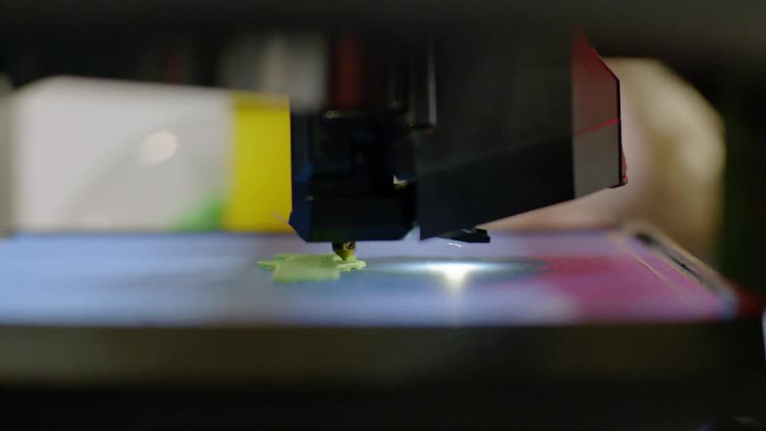 A 3d printer begins to print an object while a child watches