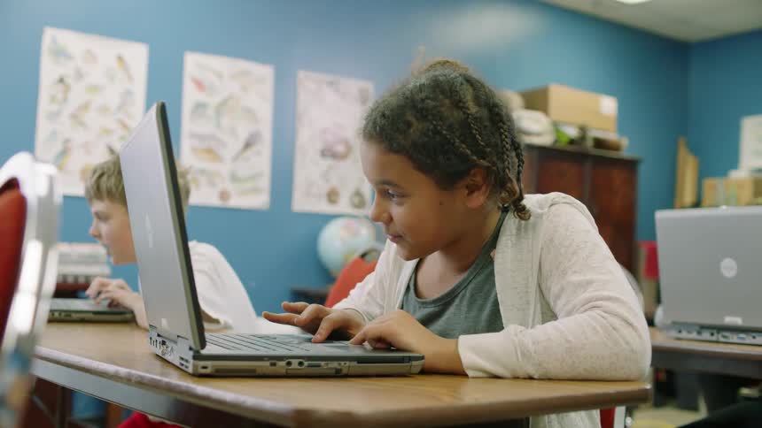 A kid is using a laptop in a classroom