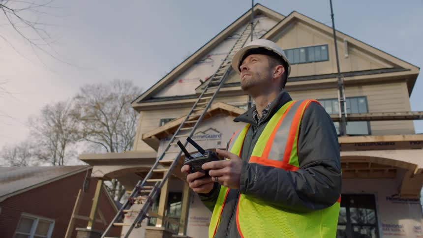 A man is operating a remote control device outside at a construction site during the day