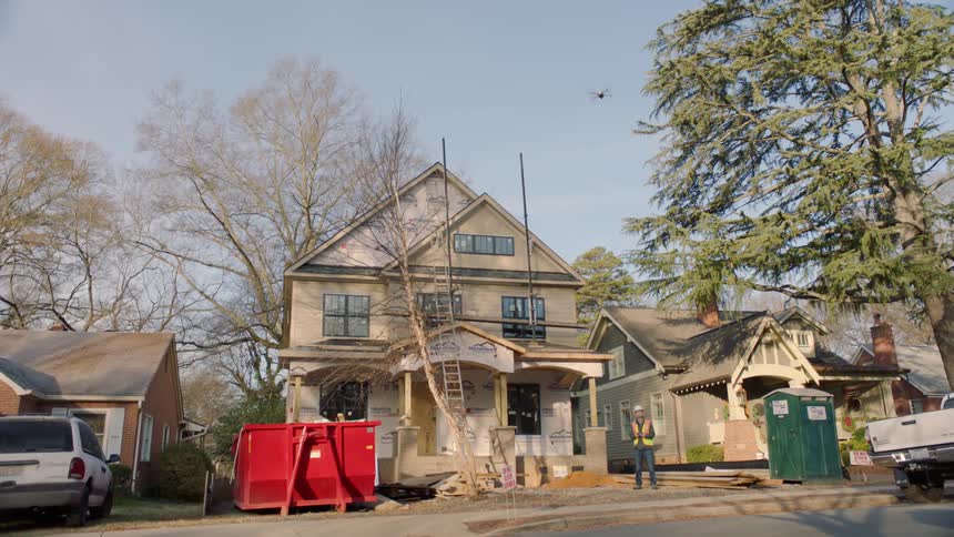 A construction worker stands in front of a house