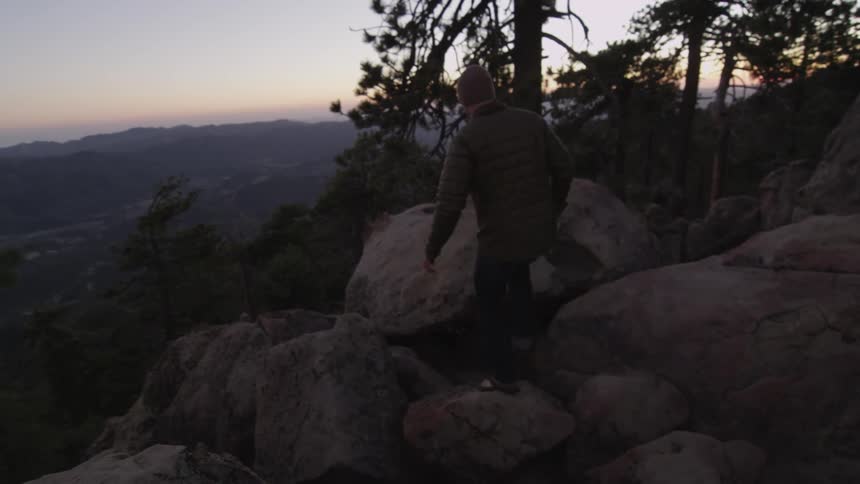 A man is walking along boulders
