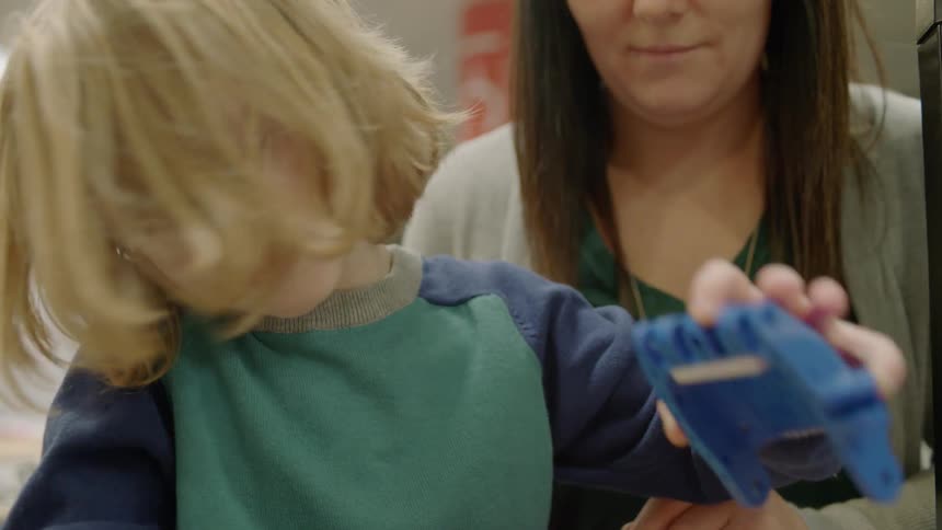 A woman and child play with some toys on the table