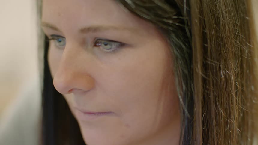 A woman looks forward blinking