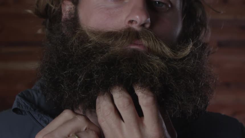 A man staring while putting his hands through his beard
