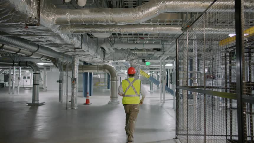 Worker in helmet walks through factory