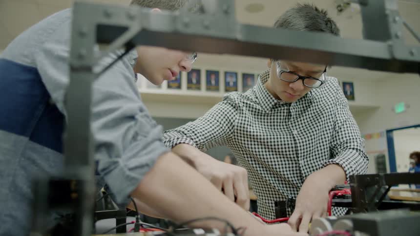 Two young men work on an electrical board