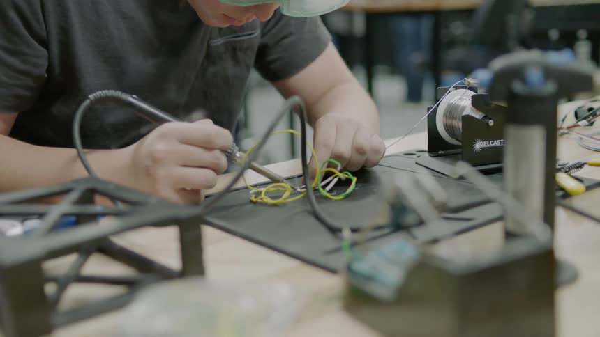 A man is using a soldering iron on some wires