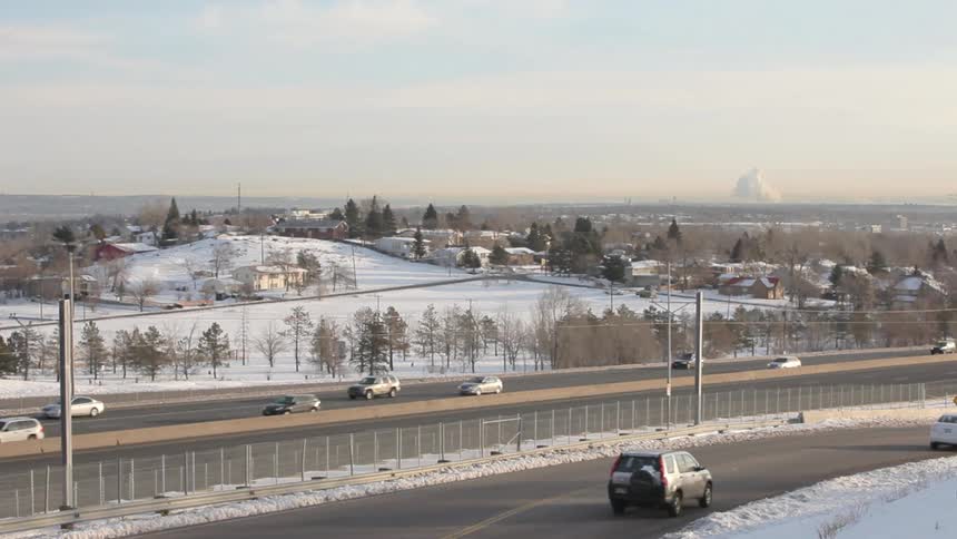Vehicles travel a large highway beside a snow covered rural town