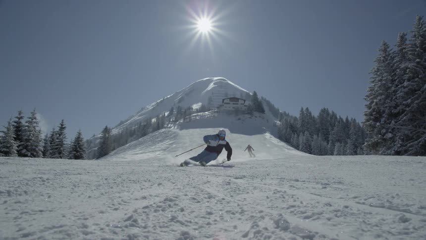 Snowboarders descend down a snowy slope