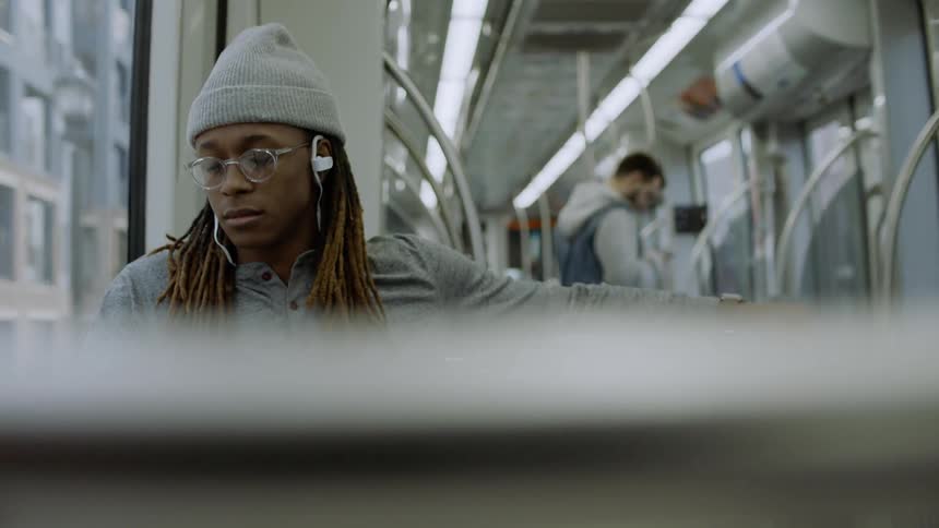 A man rides a subway while wearing headphones