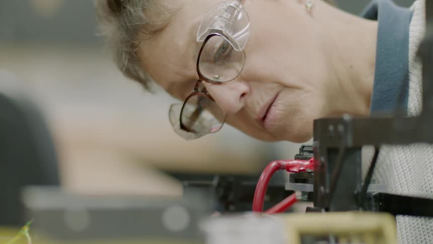 A woman is examining a machine as it runs