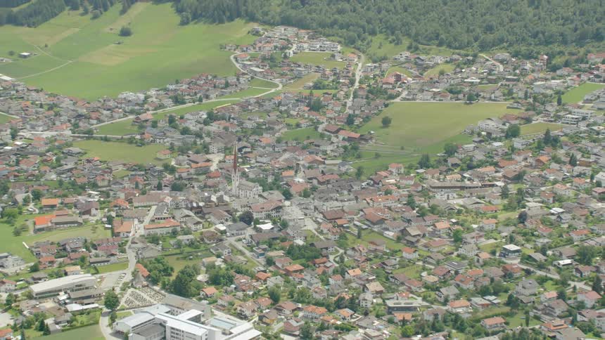 A village spreads out along a mountain valley floor during the day