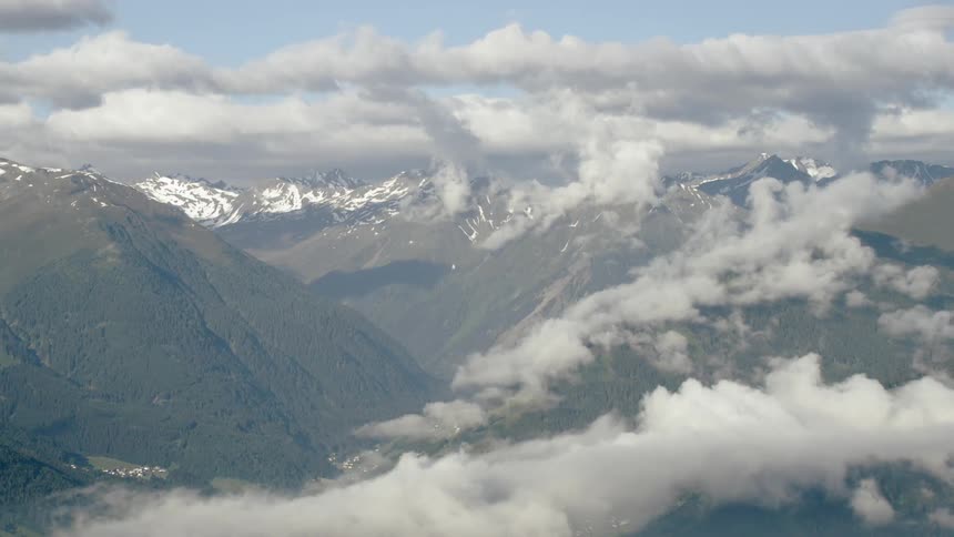 Clouds hang above tall mountains