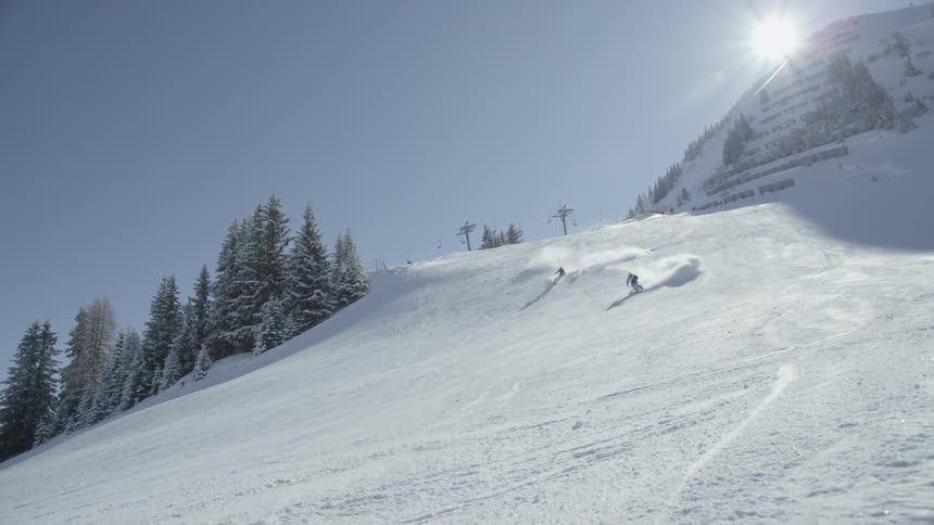 Skiers are traveling down a ski slope during the day