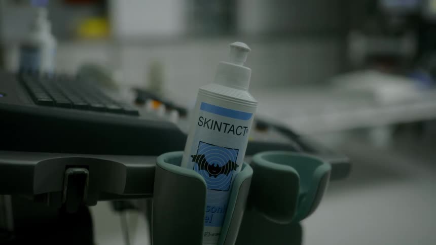 A bottle of electrode gel sits near a keyboard in a medical setting