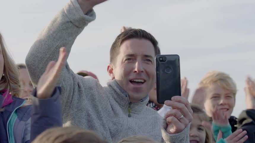 A man records something on his phone from a crowd