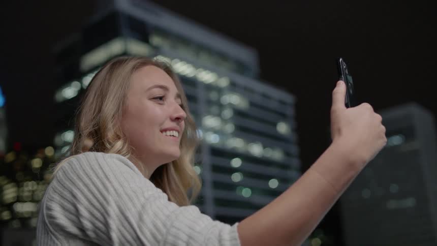 A woman takes a selfie outside and blows a kiss