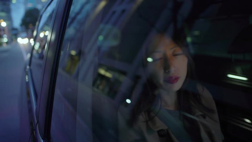 A woman looks out the window as it drives her at sunset