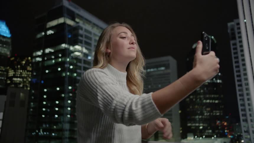 Woman blows a kiss at her phone in a city