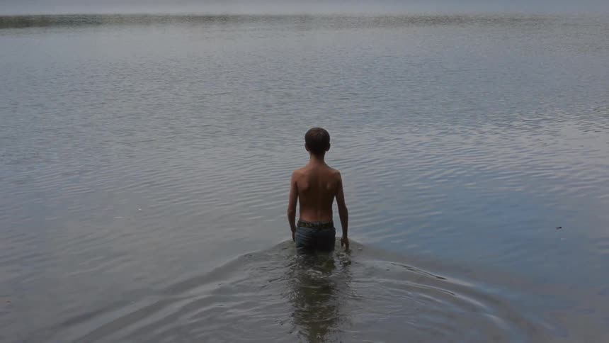A child walking into a lake